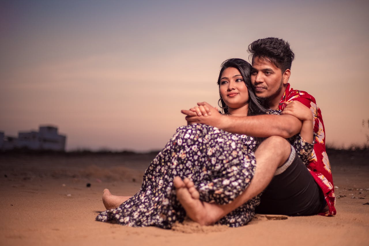 A loving couple embraces on the sandy beach of Chennai, India during a warm sunset.