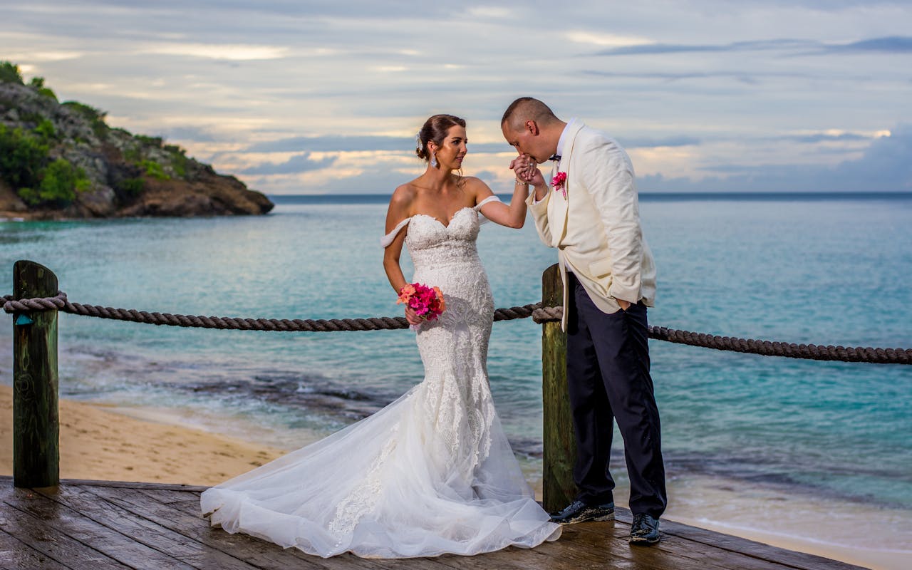 Newlyweds share a romantic moment on a beachfront deck in Antigua, captured during sunset with the ocean as a backdrop.